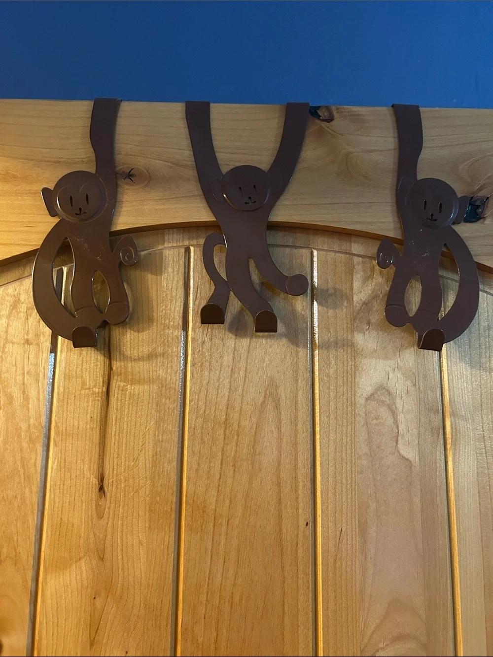 A set of 3 whimsical brown metal monkey over-the-door hooks